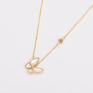 Macro detail of gold butterfly pendant with white shell inlay and sparkling crystals
