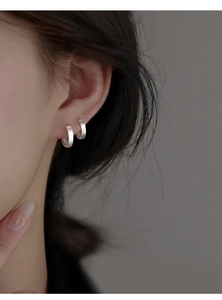 Close-up of matte S925 sterling silver hoop earrings worn by a model in a minimalist style