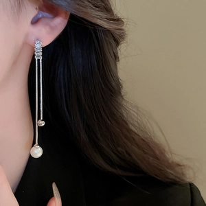 Macro view of long tassel earrings featuring silver chains, zircon stones and white pearls
