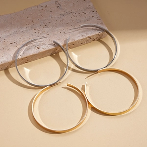 Flat round geometric hoop earrings in gold and silver finish on a textured stone base