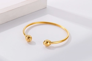 Detailed view of gold minimalist open cuff bracelet featuring smooth spherical ends