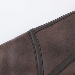 Detail of dark brown leather jacket featuring high-quality stitching and piping textures