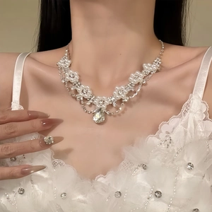 Close-up of model wearing floral diamond necklace with pearl and teardrop pendant