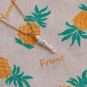 Detail of gold-plated chili pendant with white enamel and pink star patterns