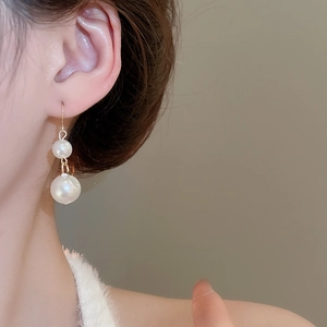 Detail shot of elegant double pearl drop earrings featuring white pearls and gold hooks