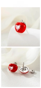 Macro shot of red enamel apple earrings with heart-shaped zircon and screw back closure