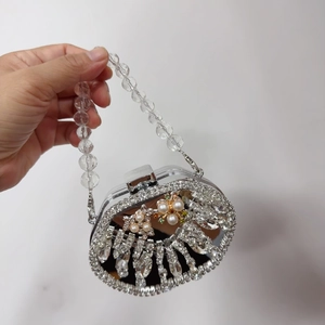 Detailopname van mini avondtas met strass-steentjes, parelblemen en transparant kralenhandvat