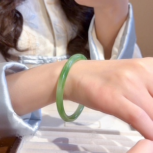 Detailed view of a green resin bangle with jade texture worn by a model in soft lighting