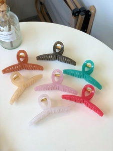 Detailed top view of various colorful 11cm hair claws arranged on a white round table