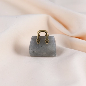 Detail of grey natural stone handbag pendant with gold handle on silk fabric