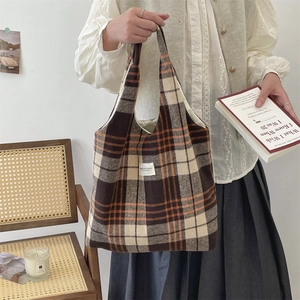 Dettaglio di una borsa tote vintage in lana a quadri con etichetta in tessuto bianca