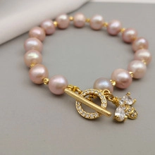Detail of pink pearl bracelet featuring golden bee charm and sparkling toggle clasp