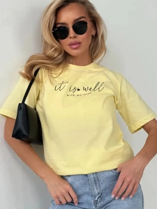 Λεπτομέρεια κίτρινου βαμβακερού T-shirt με μαύρο τύπωμα γραμμάτων και στρογγυλή λαιμόκοψη