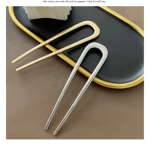 Detail view of gold and silver U-shaped metal hairpins displayed on a sleek black tray
