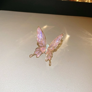 Macro detail of pink enamel butterfly ear cuff with gold alloy edges on beige leather