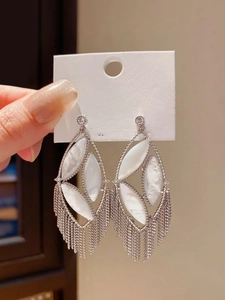 Detailed view of silver oval earrings with white mother-of-pearl and long chain tassels