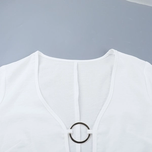 Detailed close-up of white knitted V-neckline with decorative silver metal ring buckle