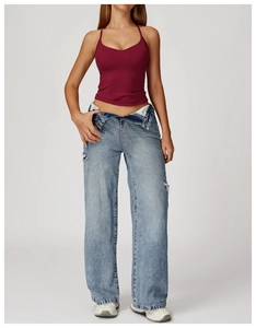 Dettaglio del top da yoga bordeaux con schiena incrociata e jeans in denim strappati
