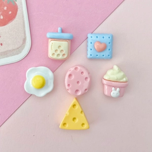 Flat lay of cute resin food charms including milk tea, fried egg, and cheese for DIY crafts