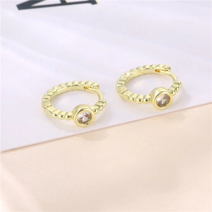 Golden hoop earrings with round zircon stones and beaded texture on white background