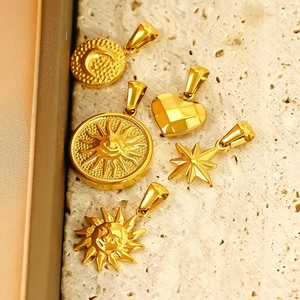 Polished gold celestial pendants with sun and moon motifs on a beige stone background