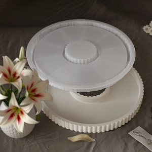 Detail of round wave-edged silicone mold with finished white plaster tray and lilies
