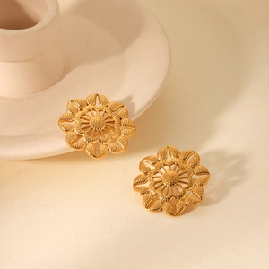 Gros plan détaillé de boucles d'oreilles fleurs dorées vintage sur socle céramique