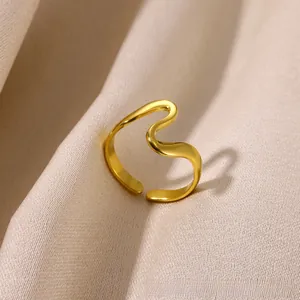 Detailed macro shot of a golden wave-shaped adjustable ring on champagne silk fabric