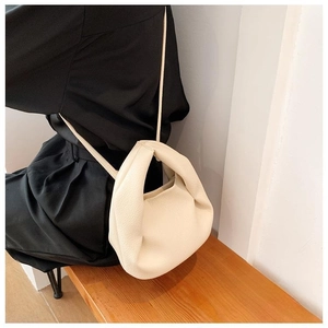 Detail of minimalist pleated cloud bag in off-white faux leather with shoulder strap
