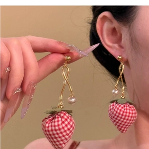 Macro detail of strawberry drop earring with red plaid fabric and small pearl accent