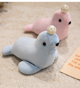 Detail of soft blue and pink plush seal toys with decorative headwear on a cozy rug