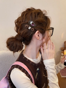 Detail showing plush brown and polka dot hair clips worn on a casual low bun hairstyle