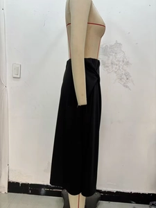 Detail shot of the waist knot and pleated texture on the elegant black midi skirt
