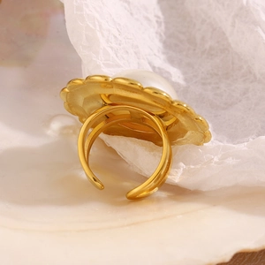 Macro view of gold plated flower ring with pearl inlay on shell background