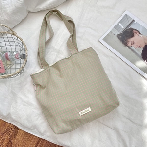Detail of pink and green checkerboard canvas tote bag with Scrakka brand label on fabric