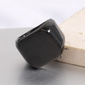 Detailed view of wide square black polished stainless steel ring on stone background