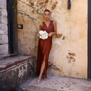 Détail d'une robe de soirée en satin rouge rouille avec col en V profond et noeud à la taille