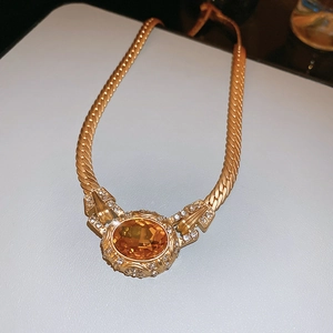 Detailed macro view of vintage gold woven necklace with amber stone and zircon crystals