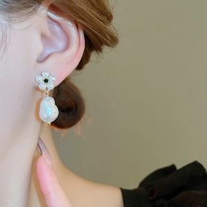 Close-up of a vintage baroque pearl flower earring worn on an elegant model ear