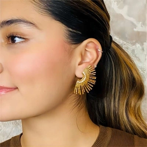 Close-up of golden ray ear studs with inlaid zircons worn on a model's earlobe