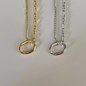 Detail view of gold and silver minimalist necklaces with asymmetric chain and twisted ring