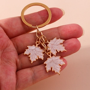 Detailed close-up of golden keychain with three white marble texture maple leaf pendants