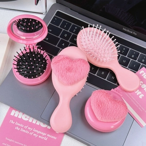 Pink heart plush air cushion hairbrush and folding mirror comb set on laptop keyboard
