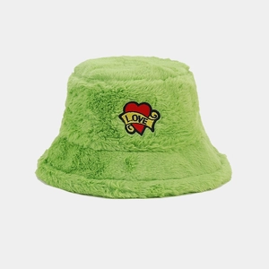 Détail du chapeau bob en peluche vert herbe avec écusson brodé en forme de cœur