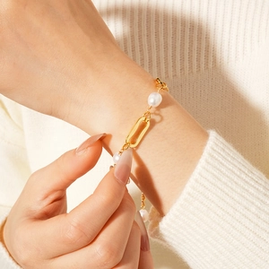 Detail view of gold-plated chain bracelet with freshwater pearls on a knit sleeve