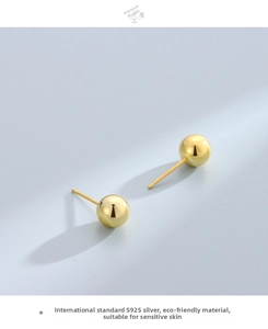 Macro detail of minimalist gold S925 sterling silver sphere stud earrings with polished finish