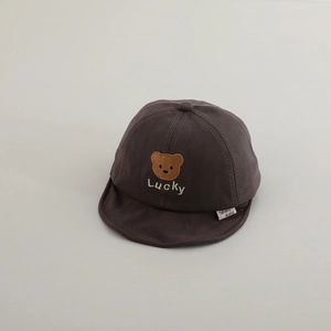 Close-up of baby peaked cap with brown bear embroidery and Lucky text on soft cotton