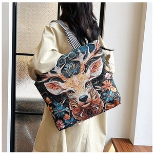 Detail of embroidered tote bag with floral deer pattern on woman in beige trench coat