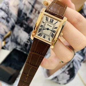 Close-up of a ladies rectangular gold watch with brown crocodile leather strap on a wrist