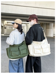 Street style shot of two large canvas messenger bags in army green and off-white colors